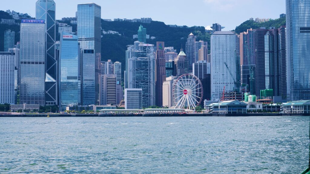 Stunning view of Hong Kong skyline with skyscrapers and observation wheel from Victoria Harbour.